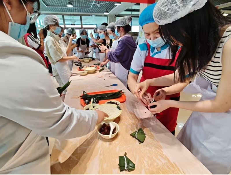 大学生与饮食师傅包粽子共度端午...